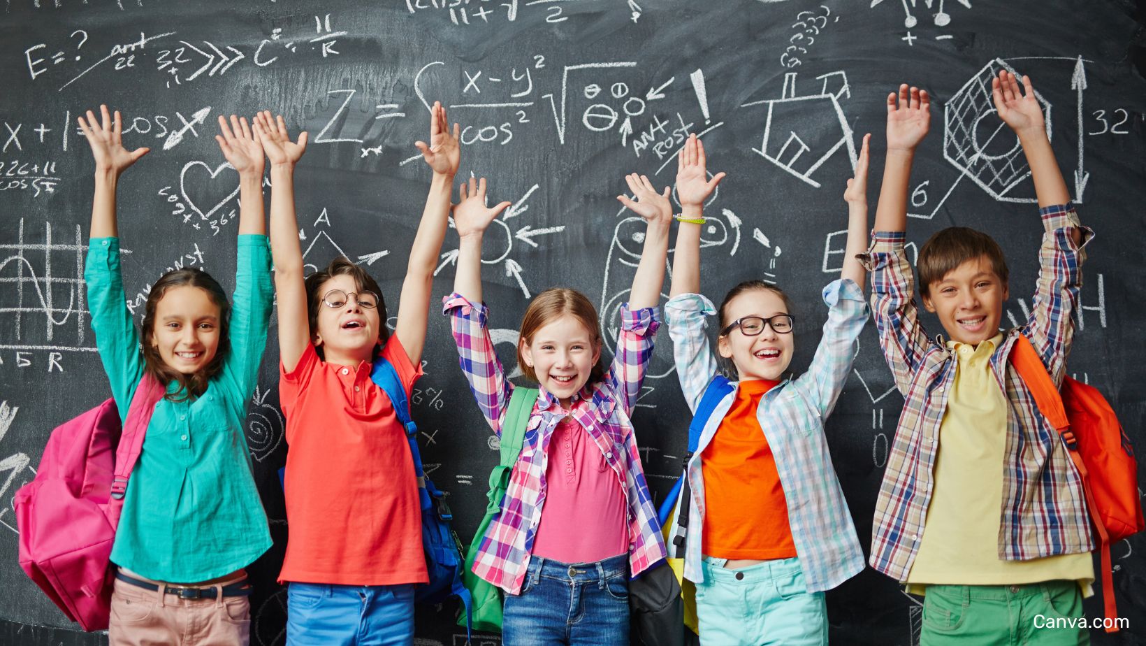 5 enfants d'origines éthniques différentes levant les bras devant un tableau noir recouvert de dessins à la craie à l'école