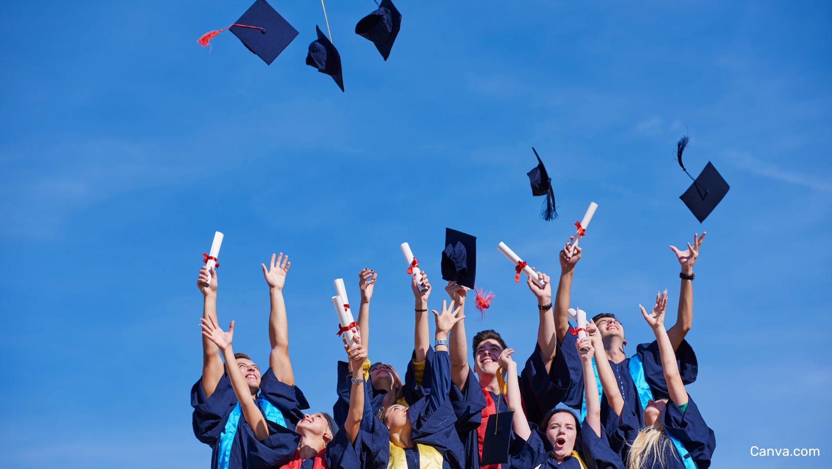 groupe de jeunes diplomé.e.s lançant leur chapeau en l'air et agitant leurs diplômes.