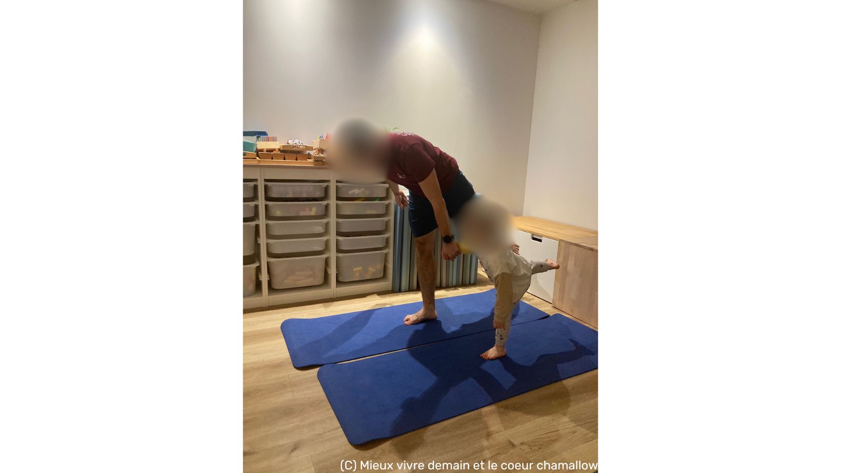 père et son fils se tenant la main, et pratiquant une posture de yoga sur un pied en se regardant. Atelier ayant lieu dans les locaux de l'Étoile des familles