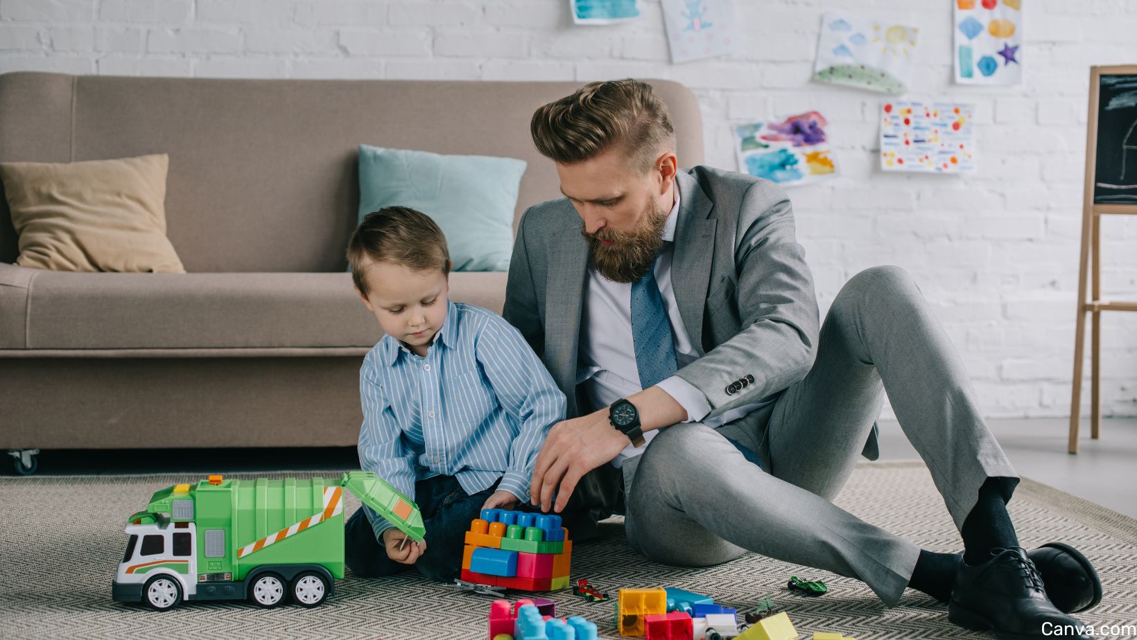 jeune papa en costume jouant au sola vec son fils avec des blocs de construction coloré et un camion